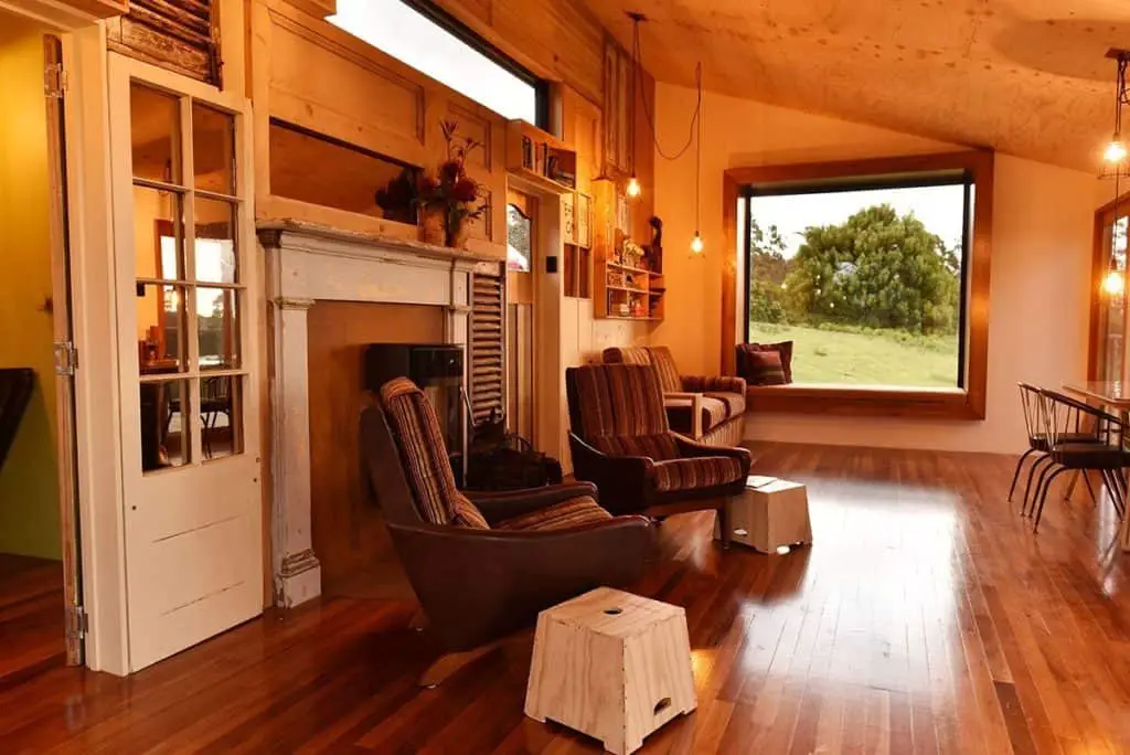 The Container - recycled shipping container home living room with large picture window and a mixture of recycled furniture and interior finishes