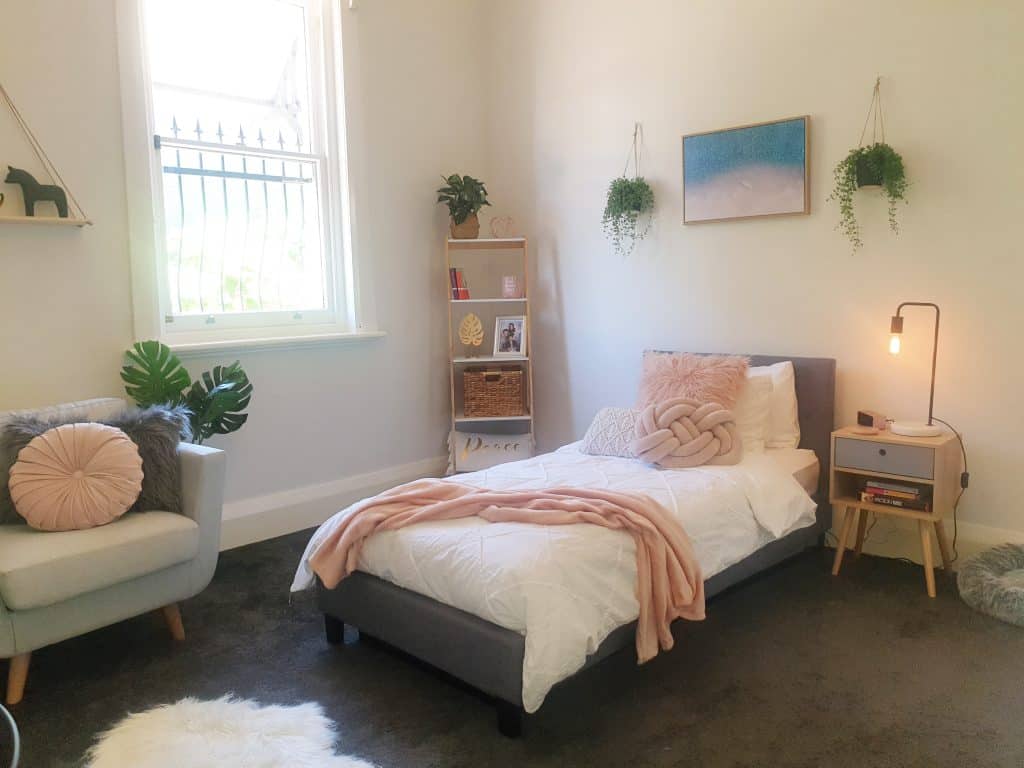 DIY bedroom makeover - whole room view of bed, bookshelf and chair. Hanging plants and fluffy rug.