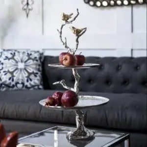Bird and tree cakestand on display on table with apples on both levels.