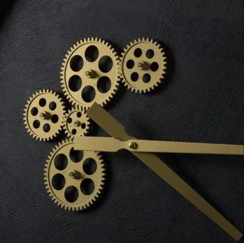 Black and gold wall clock with exposed mechanics close up of exposed gold mechanics detail