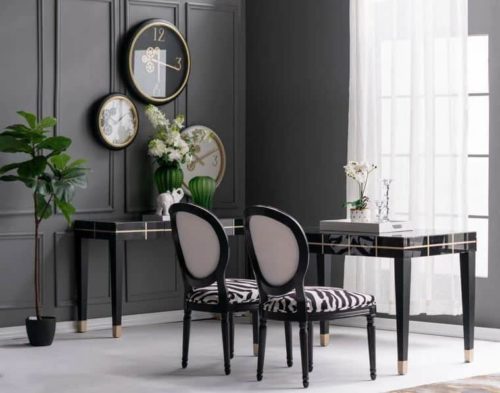Black and gold wall clock with exposed mechanics featured in a collection of other clocks hung on a wall in a glamorous home.