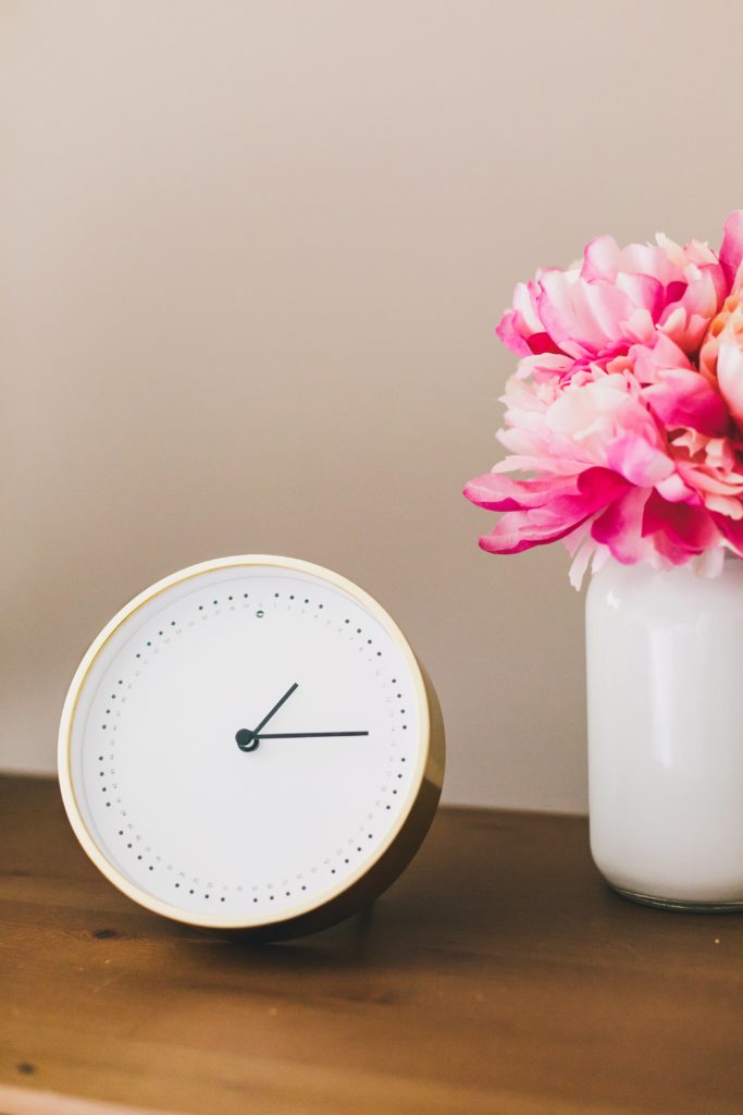 Minimalist living decor clock and flowers on table