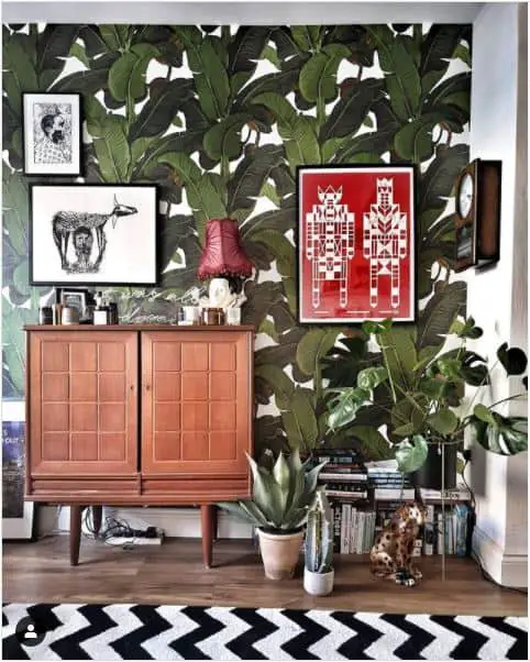 70s wallpaper revival. Living room with bold tropical leaf print wallpaper.